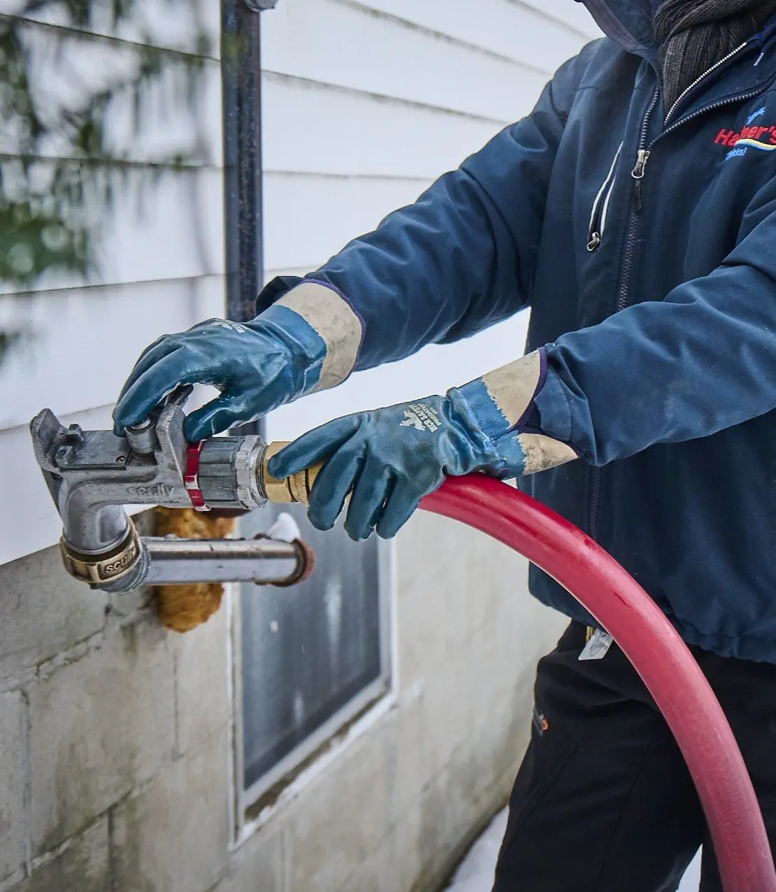 Patchogue Fuel technician connecting a delivery hose to a home heating oil fill pipe in winter