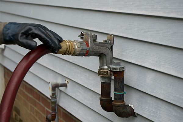 Oil burner service technician checking a heating oil fill line in Patchogue, NY